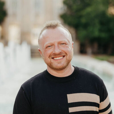 Cassidy is a white male with short red hair, a black shirt and tan vertical lines.