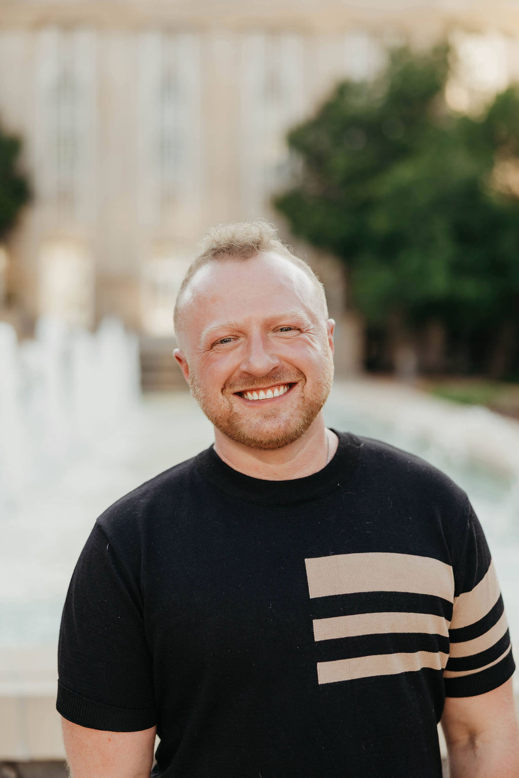 Cassidy is a white male with short red hair, a black shirt and tan vertical lines.