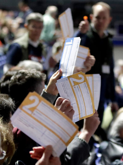 Caucus goers in Des Moines, Iowa hold up their first votes for their 2020 Democratic presidential candidate pick.