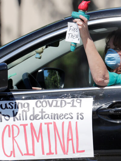 A woman drives in a caravan protesting conditions detainees face in ICE detention centers.