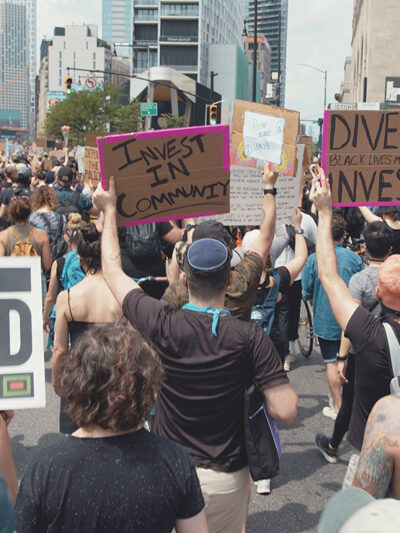 Protesters marching in a demonstration with signs calling on officials to divest from police and invest in communities.