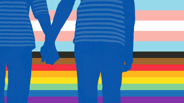 Two people holding hands with LGBTQ+ flag behind them