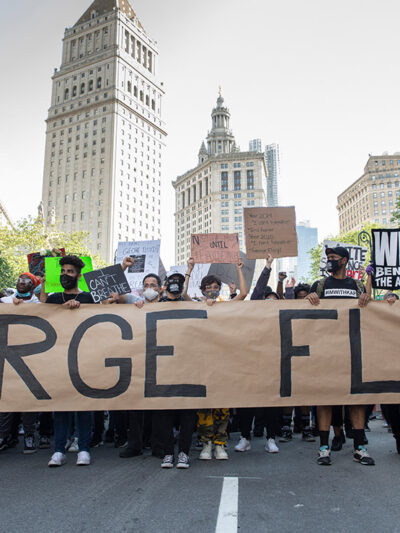 Black Lives Matter demonstrators marching with a large banner with George Floyd's name.