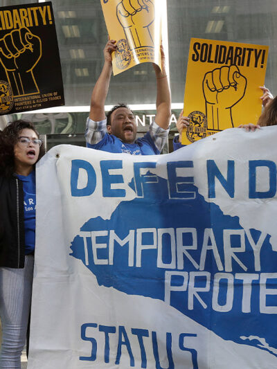 Supporters of temporary protected status immigrants hold signs and cheer at a rally in support of a program that lets immigrants live and work legally in the United States.