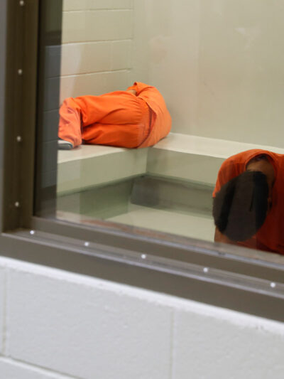 Three detainees waiting together inside a room to be processed at a detention facility.