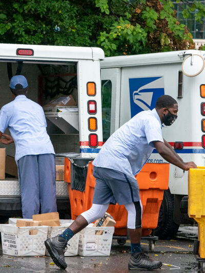 Letter carriers load mail trucks for deliveries at a U.S. Postal Service facility.
