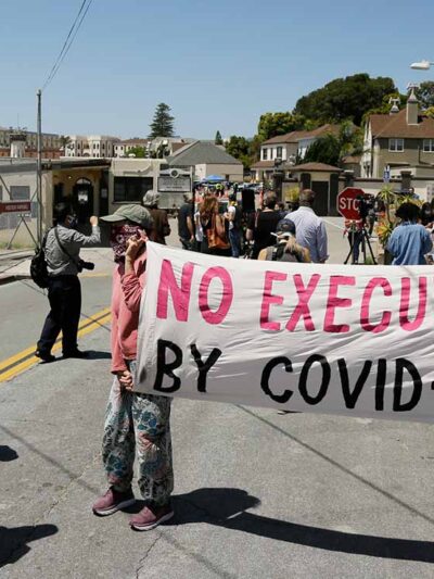 A sign reading "No Executions by Covid-19" is seen at a protest