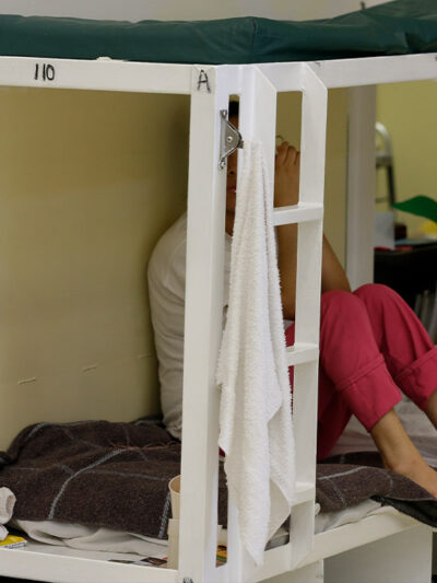 A detainee sits on a bunk in a women's area at an immigration detention center.