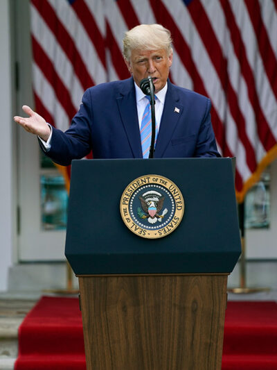 President Donald Trump speaks about podium with presidential seal during an event in the Rose Garden of the White House.
