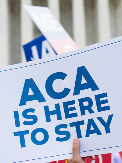 Affordable Care Act Supporter waves sign that reads "ACA is here to stay" outside of the Supreme Court.