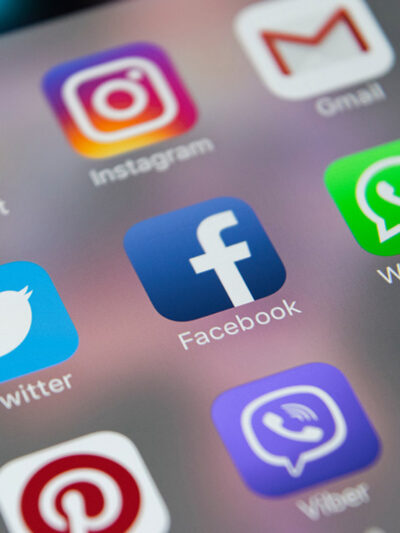 Icons of social media apps including Facebook, Instagram, Twitter, and Snapchat on an iPhone screen.