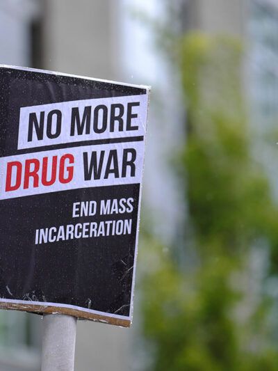 Black and white protest sign reads: "No More Drug War, End Mass Incarceration"