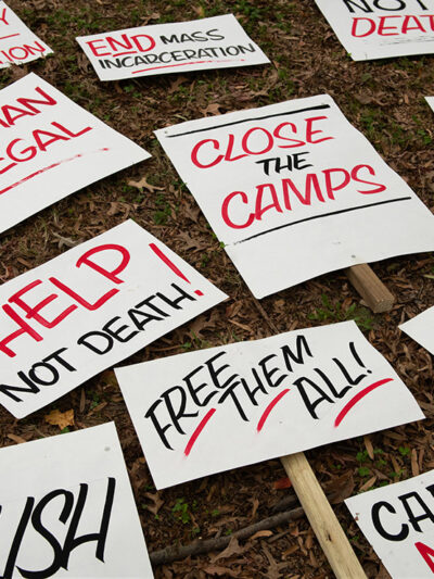 Several signs with calls to end mass incarceration and advocate for the rights of immigrants lying in the grass.