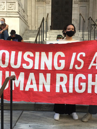 Protesters carrying a banner with the text "housing is a human right.