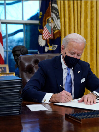 President Joe Biden signs his first executive order in the Oval Office of the White House.