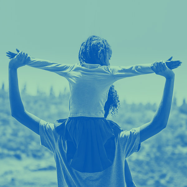 Child sitting on parent's shoulders with arms outstretched.