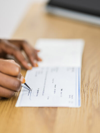 A black woman signs a cashier's cheque.
