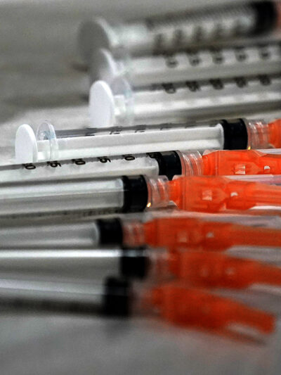 Syringes loaded with the Moderna COVID-19 Vaccine spread on a clinic table