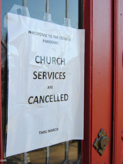 A sign taped to the door of a church announcing services are cancelled due to COVID-19.