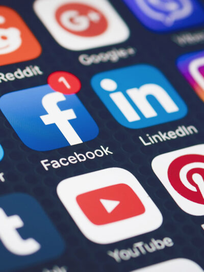 Social media icons including Facebook, LinkedIn, and YouTube on a phone screen.