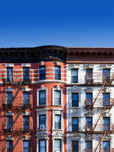 New York City block of old historic apartment buildings in the East Village of Manhattan, with clear blue sky background.