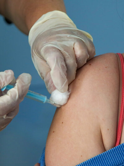 A Covid-19 vaccinator administers the Oxford/AstraZeneca vaccine to a woman at a vaccination centre in London