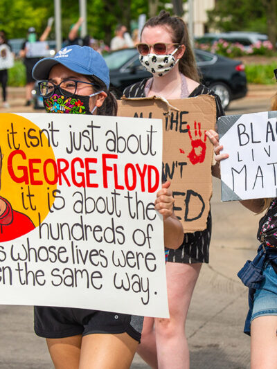 BLM protester holding a sign that says, "It isn't just about George Floyd it is about the hundreds of others whose lives were taken the same way."