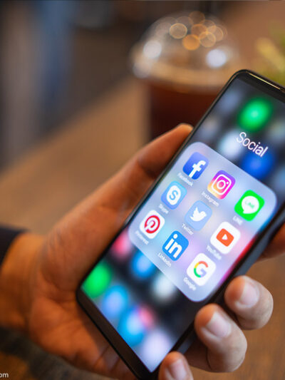 Man holding iPhone with social media icons displayed on the screen