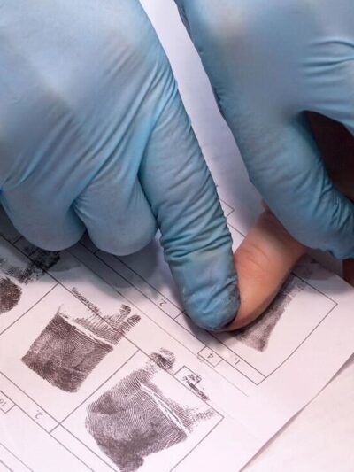 crime investigator wearing gloves fingerprinting person