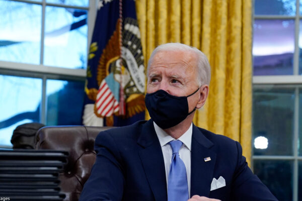 A photo of President Biden in the Oval Office wearing a mask.