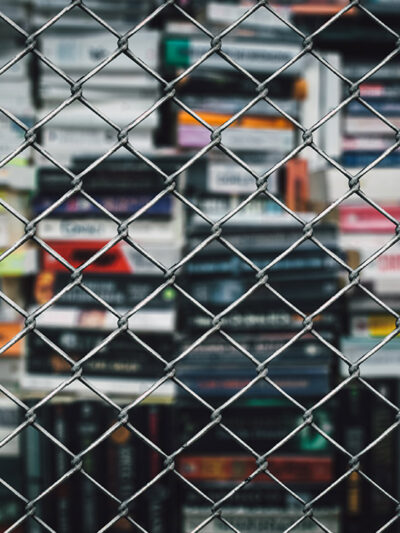 A stack of books behind a chain-link fence.