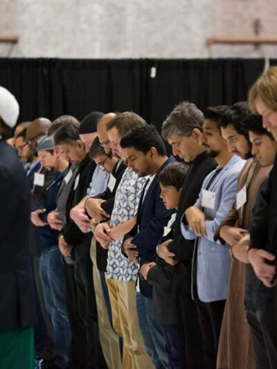 Imam Kariye standing in front of the row of people in prayer.