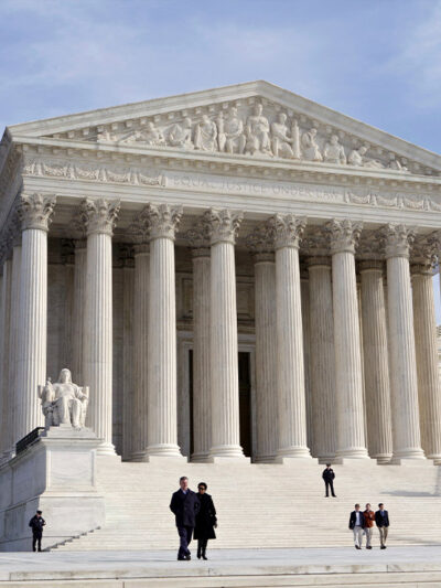 The front of the Supreme Court, as a few people are walking up and down its stairs, on a sunny day in 2012.