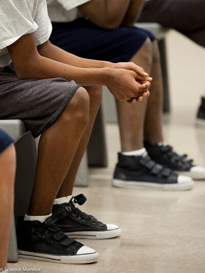 Four children (with faces hidden) sitting inside a detention center.