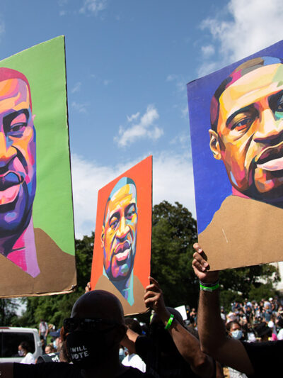 Protesters holding signs depicting George Floyd.