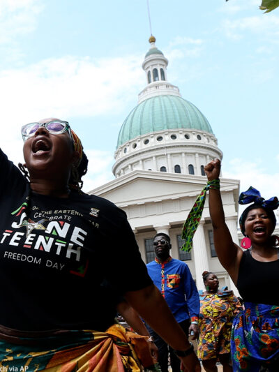 Marchers commemorating Juneteenth walking with fists raised in front of the Old Courthouse in St. Louis.