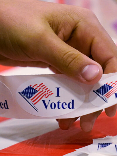 A volunteer prepares "I Voted" stickers at a polling station.