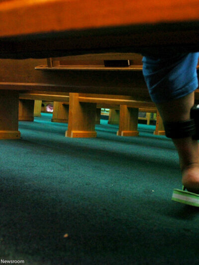 A woman pulls up her pant leg and shows her ankle monitor.