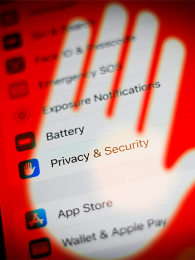 A cellphone screen with its privacy and security settings covered by a transparent hand with a red background.