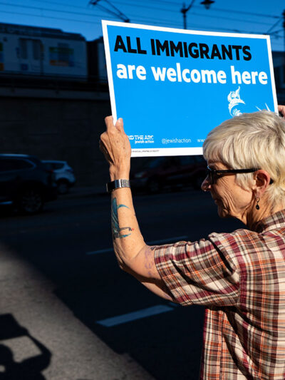 Protester holds a sign that says All Immigrants are Welcome Here.