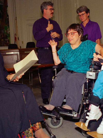 Judy Heumann, center wheelchair, is sworn in as U.S. Assistant Secretary for Special Education and Rehabilitative Service by Judge Gail Bereola, left, on June 29, 1993. Standing at left is Berkeley Mayor Loni Hancock with sign language interpreter...