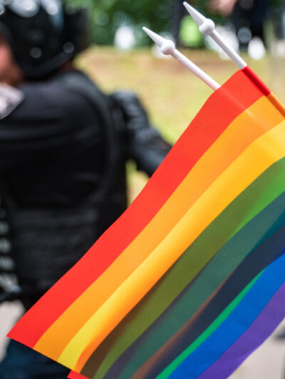 LGBTQ flag with police in the background.