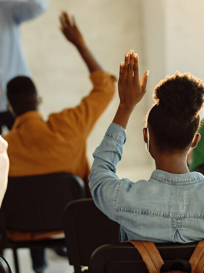 Students raising their hands in a classroom.