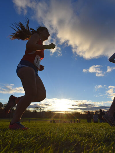 Several silhouettes of individuals running track.