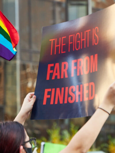 Someone holding a sign that says The Fight Is Far From Finished.