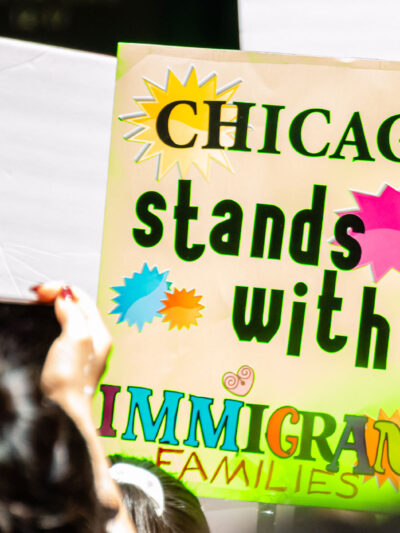 A demonstrator holds a sign that reads "Chicago Stands With Immigrant Families".