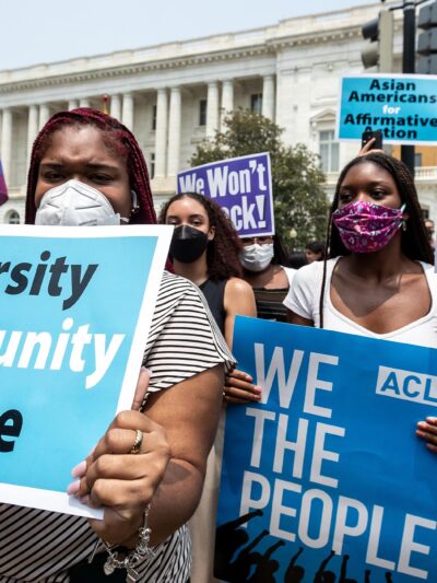 Protesters in front of the Supreme Court hold signs that read, "Diversity, Opportunity, Justice", "ACLU, WE THE PEOPLE", "Affirmative Action YES!" and "Asians for Affirmative Action".