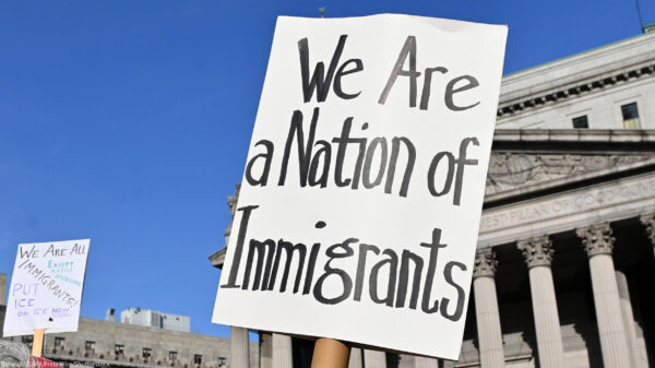 Two signs are held up during the May Day March In Manhattan, New York on May 1, 2025. The largest of the signs is in the foreground and reads"We Are a Nation of Immigrants," while the smaller in the background reads, " WE ARE ALL (EXCEPT NATIVE...