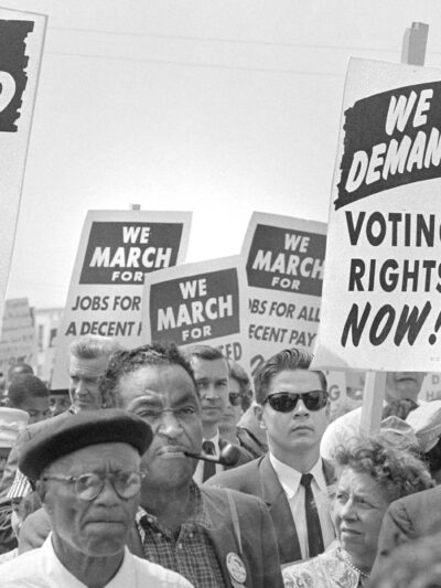 Protesters with signs at march on Washington, D.C. for Jobs and Freedom, carrying signs that read "WE DEMAND VOTING RIGHTS NOW!" and WE DEMAND AN END O POLICE BRUTALITY NOW!" on August 28, 1963.