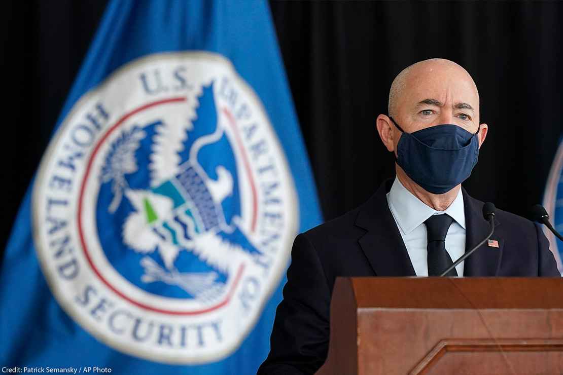 Secretary of Homeland Security Alejandro Mayorkas speaks during news conference with a U.S. Homeland Security flag behind him.